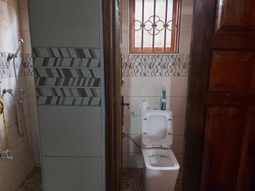 a bathroom with a toilet and a window at Charming House in Matugga Kampala Uganda in Matuga