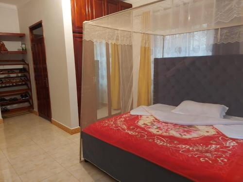 Schlafzimmer mit einem Bett mit einer roten Bettdecke in der Unterkunft Charming House in Matugga Kampala Uganda in Matuga