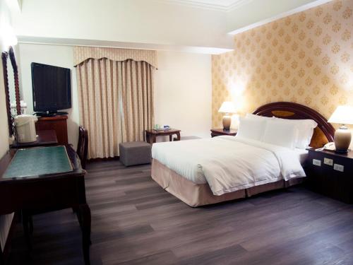 a hotel room with a bed and a flat screen tv at Hu House in Kaohsiung