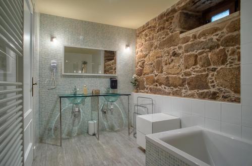 a bathroom with a stone wall and a sink and a tub at CASA DO LEAL SILVER WAY in Silleda