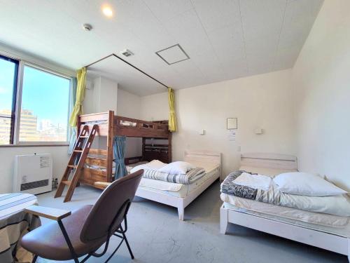 Habitación con 2 camas, escritorio y silla. en Guest House Proof Point en Kushiro