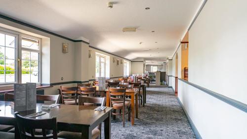 a dining room with tables and chairs and windows at The Appleby Inn Hotel in Appleby Magna