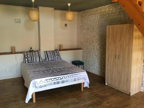 1 dormitorio con 1 cama grande y armario de madera en Gites Le Cheval Noir en Rouillac