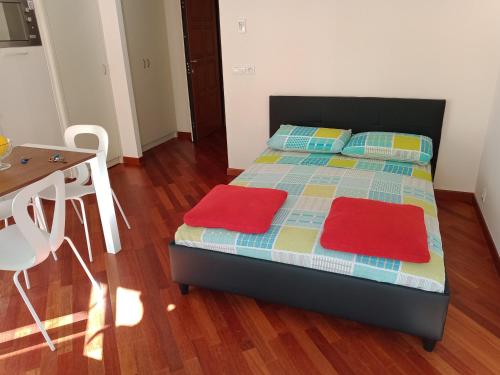 - une chambre avec un lit doté de deux oreillers rouges et d'une table dans l'établissement la perle de Menton, à Menton