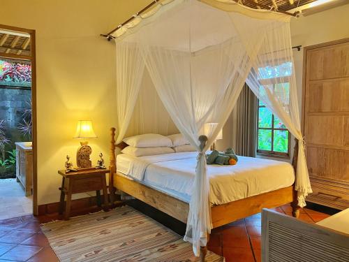 1 dormitorio con 1 cama con dosel en Desa Kerasan 5 -Luxury 2BRV 15 mins to Ubud, en Ubud