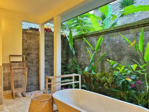 - une baignoire dans une pièce ornée de plantes dans l'établissement Desa Kerasan 5 -Luxury 2BRV 15 mins to Ubud, à Ubud