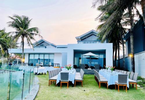 an outdoor dining area with white tables and chairs at The Ocean Villas Managed by The Ocean Resort in Da Nang