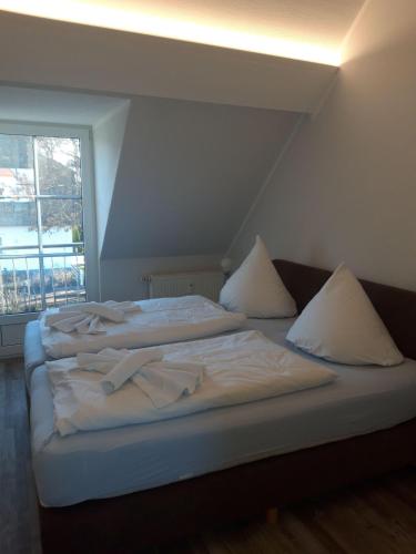 a bed with white sheets and pillows in a room with a window at Hus-Strandlust in Vitte