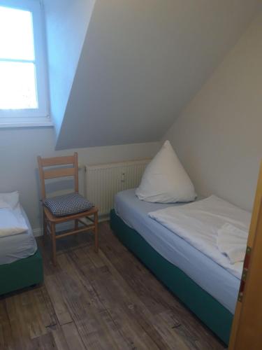 a room with two beds and a chair and a window at Hus-Strandlust in Vitte