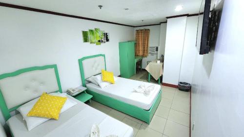 a bedroom with two beds with yellow pillows at Demiren Hotel in Cagayan de Oro
