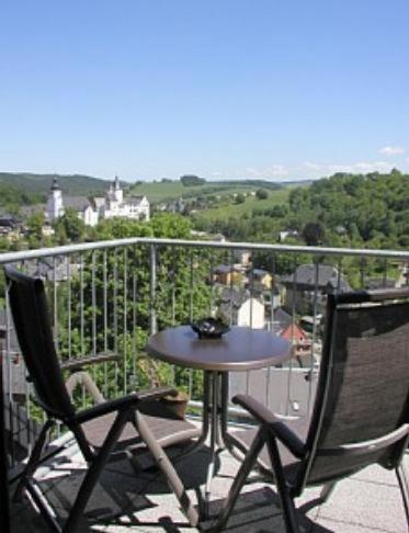 een patio met een tafel en 2 stoelen op een balkon bij Ferienperle-Erzgebirge in Schwarzenberg/Erzgebirge