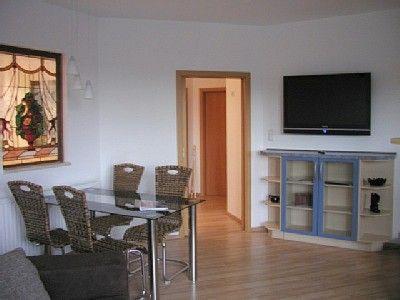 ein Wohnzimmer mit einem Tisch und einem TV an der Wand in der Unterkunft Ferienperle Erzgebirge in Schwarzenberg/Erzgebirge