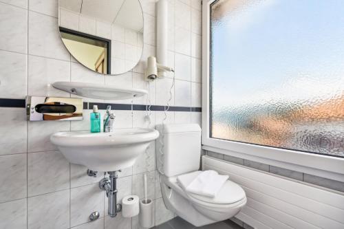 a bathroom with a sink and a toilet and a mirror at becozy du Lac Self-Check In Hotel Riviera Edition in Wädenswil