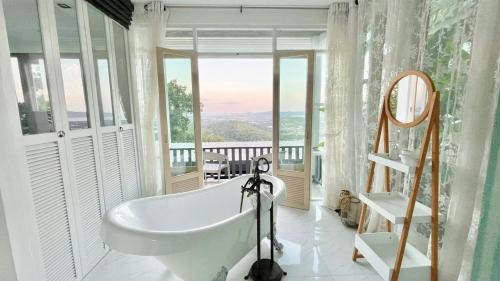 a bath tub in a bathroom with a balcony at Phuket View Coffee and Resort in Chalong