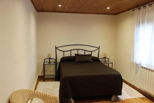 a bedroom with a bed with a black bedspread and a window at Cerezal 1, casa en plena naturaleza 