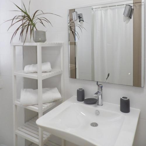 a white bathroom with a sink and a mirror at Gîte Maison Necty in Auvillar