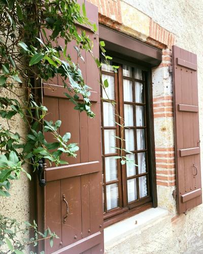 okno z brązowymi okiennicami na budynku w obiekcie Gîte Maison Necty w mieście Auvillar