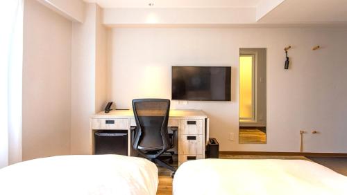 a bedroom with a desk and a television on a wall at Kissuien Stay&Food in Kyotango