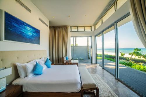 a bedroom with a bed and a view of the ocean at The Ocean Villas Managed by The Ocean Resort in Da Nang