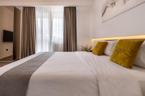 a bedroom with a large white bed with yellow pillows at Urbio Private Suites in Cluj-Napoca