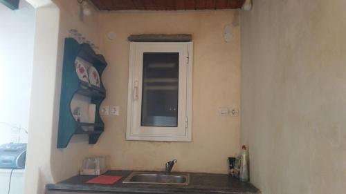 eine Küchentheke mit einem Waschbecken und einem Fenster in der Unterkunft home on the AGAPIANI sea in Kollimpithra