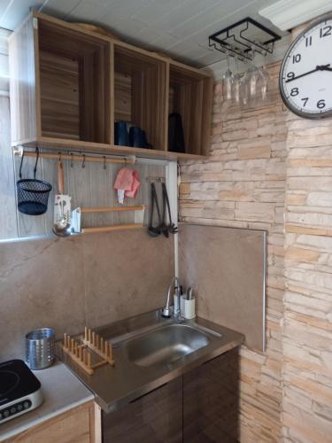 uma cozinha com um lavatório e um relógio na parede em Kata Happy Place em Praia de Kata