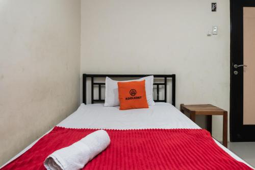 een bed met een oranje kussen en handdoeken erop bij KoolKost near State Museum of North Sumatera Medan in Medan