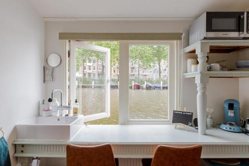 a kitchen with a sink and a large window at The Amsterdam Houseboat Family - de Jordaan in Amsterdam