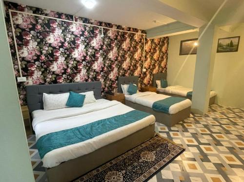 1 dormitorio con 2 camas y pared de flores en The Better Inn en Gangtok