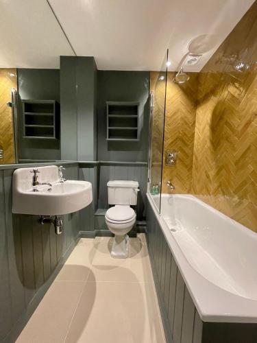 a bathroom with a toilet and a sink and a tub at The Apartments @ Quidhampton Mill in Salisbury