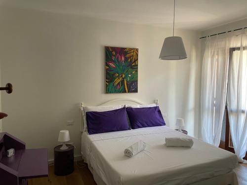 Un dormitorio con una cama grande con almohadas moradas. en Casa di Frilli - a due passi dal mare, en Porto Santo Stefano