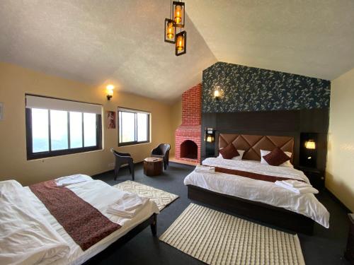 a hotel room with two beds and a fireplace at Wincliff Orchard Resort in Mukteswar