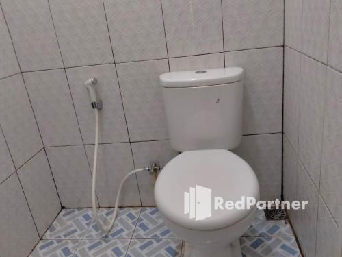 a bathroom with a white toilet in a tiled wall at Navisha Guest House Syariah near Exit Tol Batang RedPartner in Pekalongan