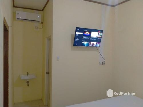 a tv on the wall of a bathroom with a sink at Navisha Guest House Syariah near Exit Tol Batang RedPartner in Pekalongan