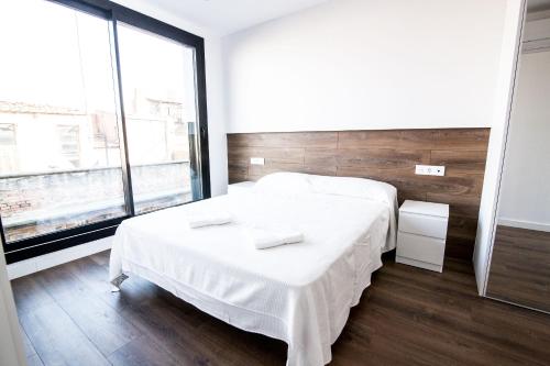 - une chambre avec un lit blanc et une grande fenêtre dans l'établissement 4-2 Apartamento de diseño en el centro de Reus, à Reus