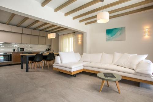 a living room with a white couch and a kitchen at Terra Pietra Luxury Villas & Suites in Lardos