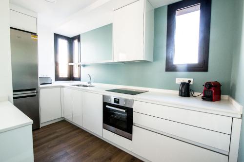 a white kitchen with white cabinets and a window at 4-2 Apartamento de diseño en el centro de Reus in Reus