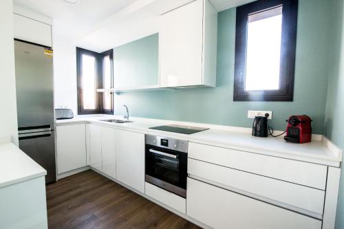 a white kitchen with white cabinets and a window at REUSIA Apartaments in Reus