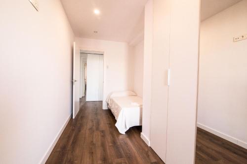 a white bedroom with a bed and a wooden floor at 4-2 Apartamento de diseño en el centro de Reus in Reus