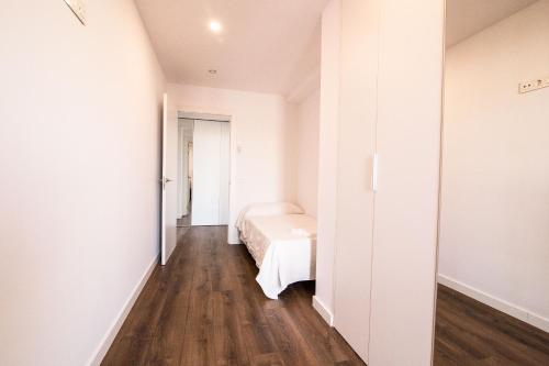 a white bedroom with a bed and a wooden floor at REUSIA Apartaments in Reus