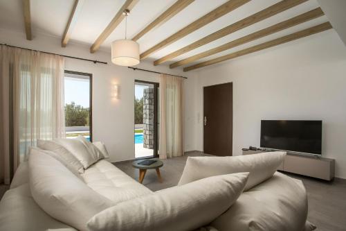 a living room with a white couch and a television at Terra Pietra Luxury Villas & Suites in Lardos