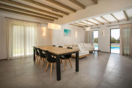 a dining room with a table and chairs and a couch at Terra Pietra Luxury Villas & Suites in Lardos