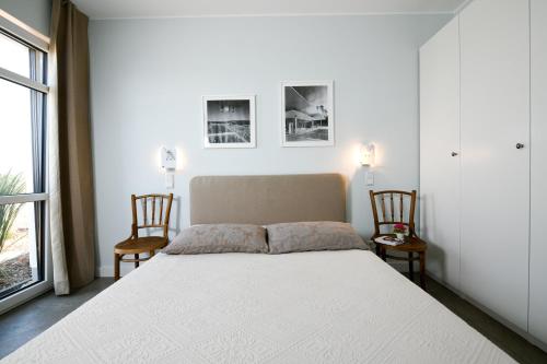 a bedroom with a large white bed with two chairs at Seehaus Mühlfeld in Löbnitz