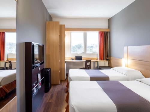 ein Hotelzimmer mit 2 Betten und einem TV in der Unterkunft ibis Jaboticabal in Jabuticabal