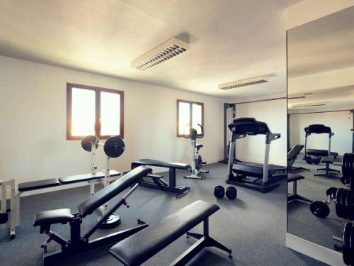 Mercure Perpignan Centre في بيربينيا: صالة ألعاب رياضية مع العديد من أجهزةالجري والأوزان في الغرفة