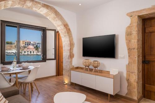 a living room with a table and a tv on a wall at Pasifai Residence - Chania old town in Chania Town