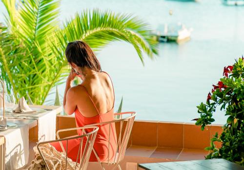 a woman in a red dress sitting at a table at Hostal la Savina in La Savina