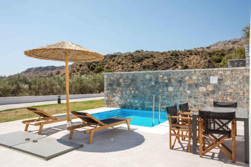 a patio with a table and chairs and an umbrella at Terra Pietra Luxury Villas & Suites in Lardos