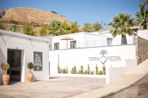 a white building with a sign that reads herberta at Terra Pietra Luxury Villas & Suites in Lardos
