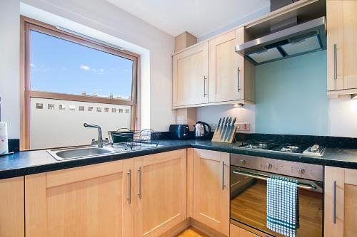 a kitchen with wooden cabinets and a sink and a window at Willowbank Road Apartments - Grampian Lettings Ltd in Aberdeen